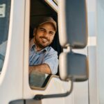 Happy truck driver looking through side window while driving his truck.